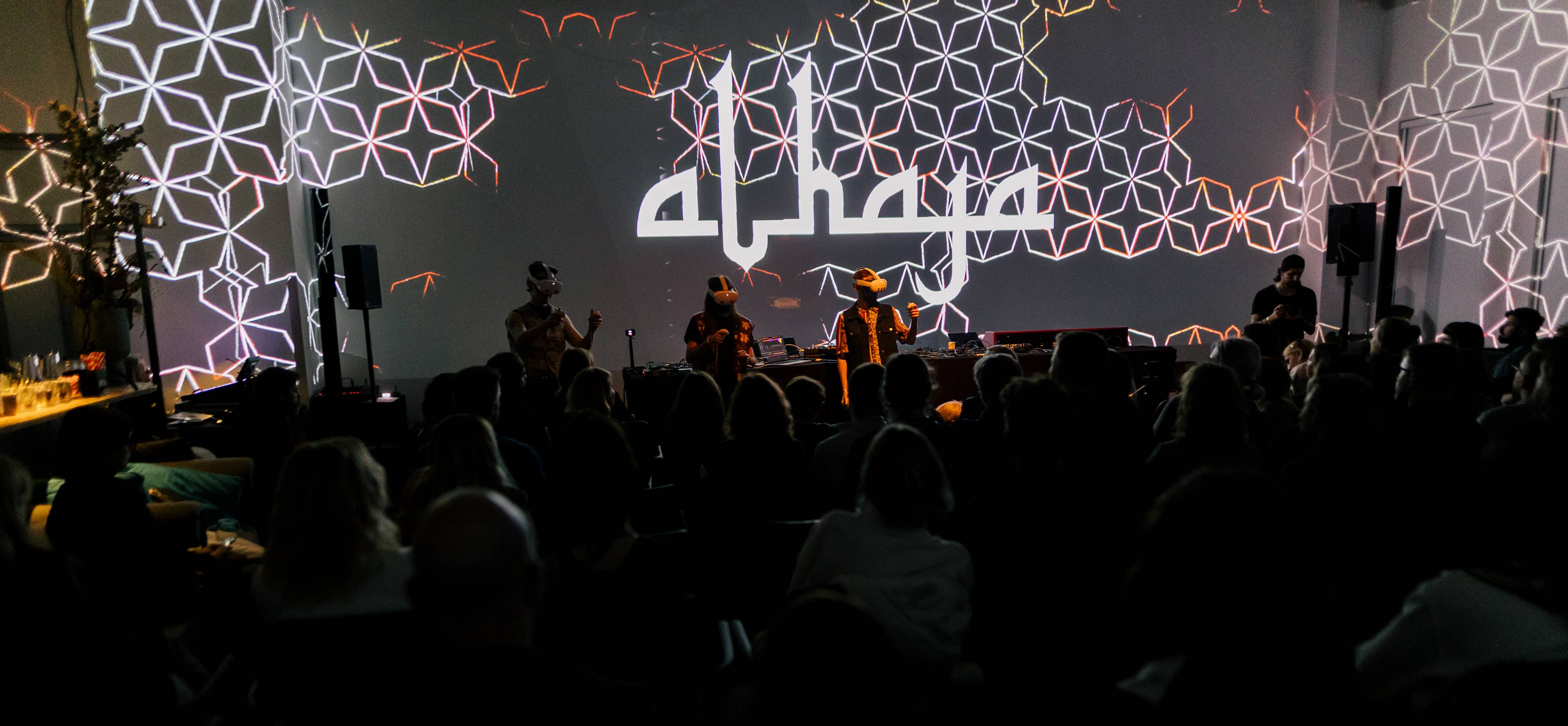 ALHAJA performers on stage with audience members watching the hybrid concert