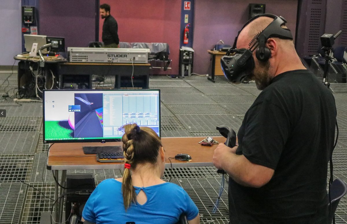 Mary Louise monitoring the virtual space on screen while Damian is inside it wearing the headset